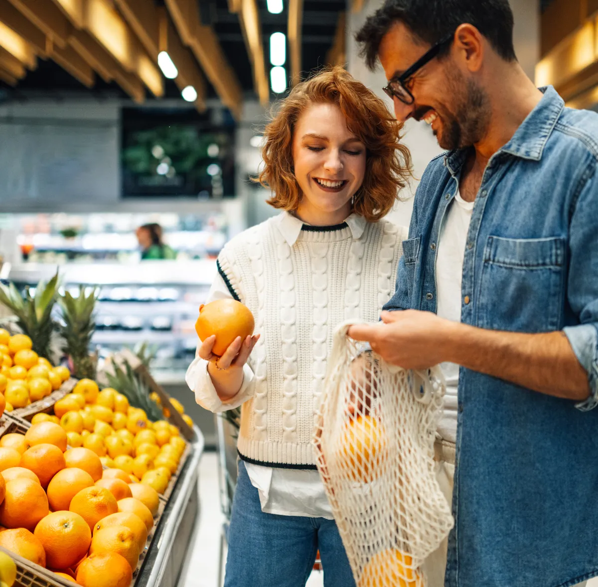 A couple choosing fresh fruit together while food shopping for a healthier diet.